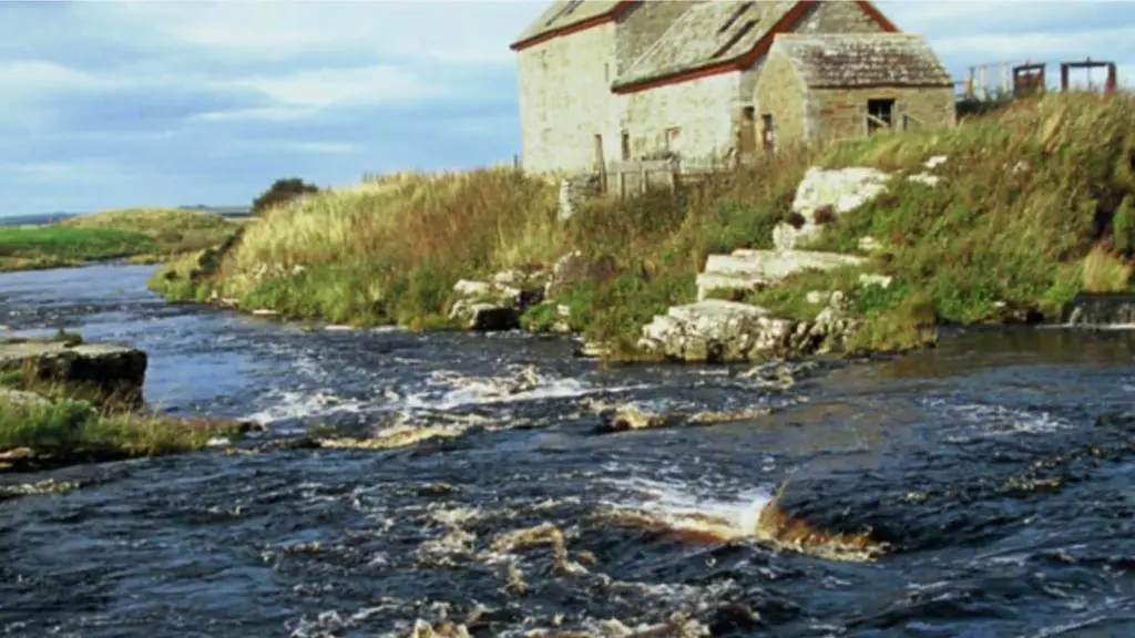 an old building sitting on the side of a river at Ella's Hoose in Wick
