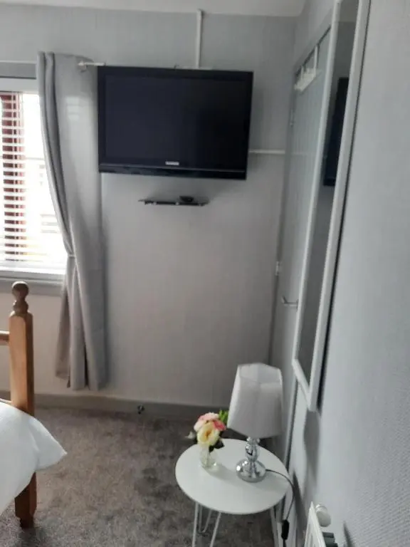 a bedroom with a tv and a table with a lamp at Ella's Hoose in Wick