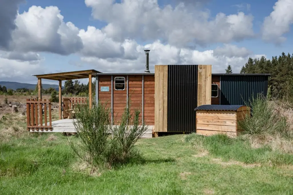 a small wooden building in the middle of a field at Highland Shepherd Huts in Nethy Bridge