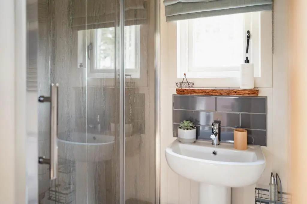 a bathroom with a sink and a shower at Highland Shepherd Huts in Nethy Bridge