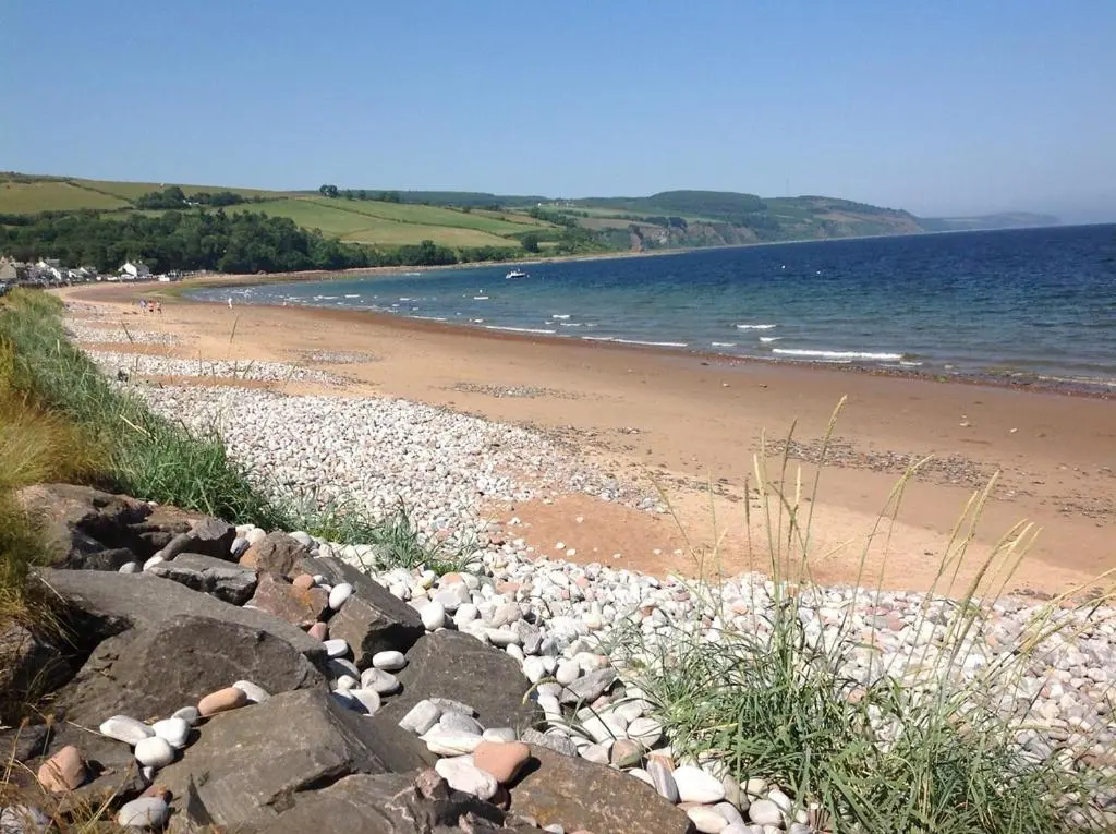 a beach with rocks and the water and the ocean at Clematis Cottage, Fortrose in Fortrose