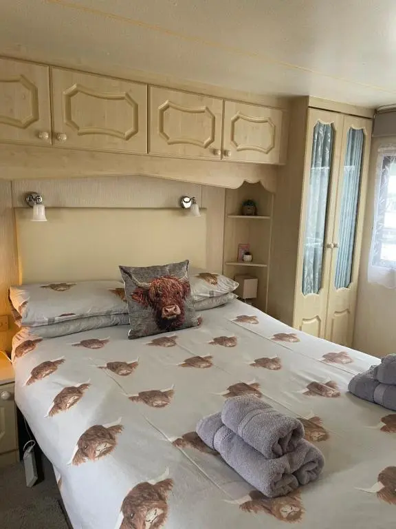 a bedroom with a large bed with towels on it at Caravan at Charleston House in Inverness