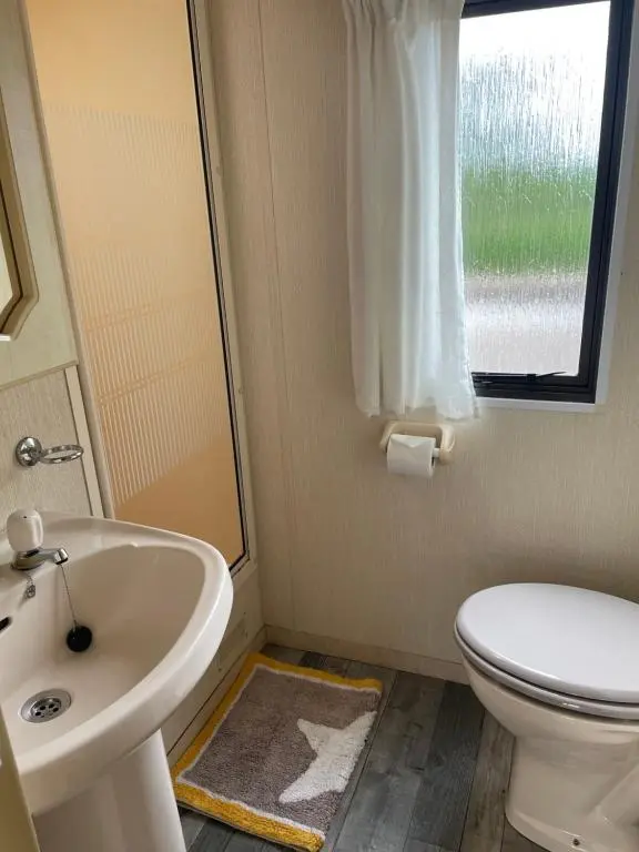 a bathroom with a toilet and a sink and a window at Caravan at Charleston House in Inverness