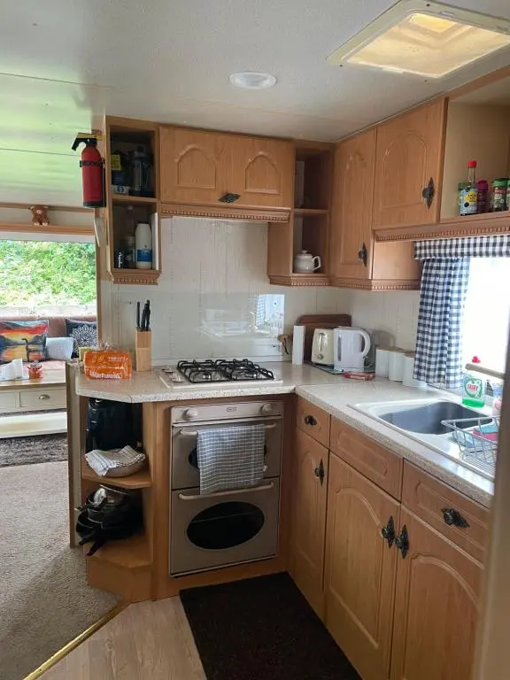 a kitchen with wooden cabinets and a stove top oven at Caravan at Charleston House in Inverness