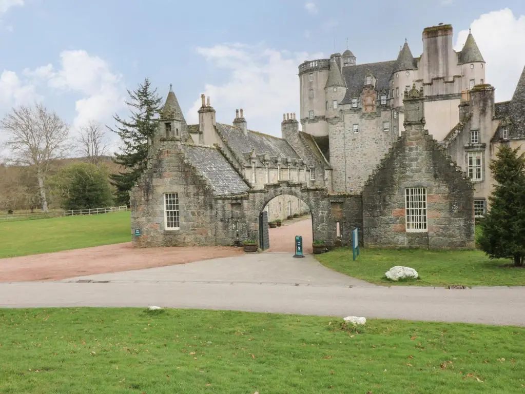 an old stone building with a gate in a field at East Wing - Castle Fraser in Inverurie