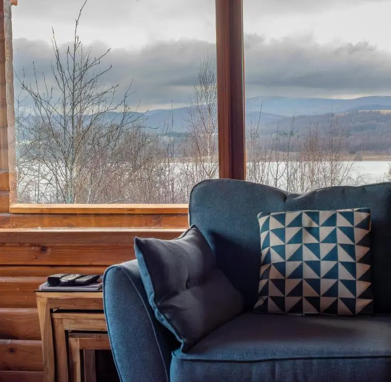 a blue couch sitting in front of a window at Loch Insh Chalets and Apartments in Kincraig