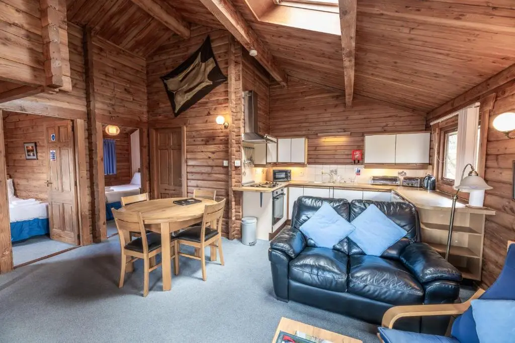 a living room with a leather couch in a log cabin at Loch Insh Chalets and Apartments in Kincraig
