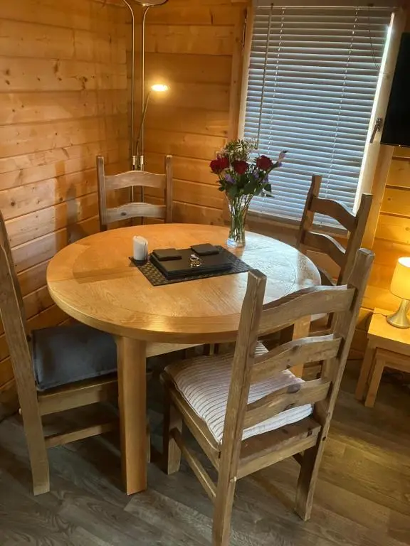 a dining room table with chairs and a tableablish at Log Cabin in the City with hot tub in Culloden