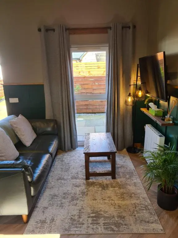 a living room with a leather couch and a coffee table at The Hide in Ullapool