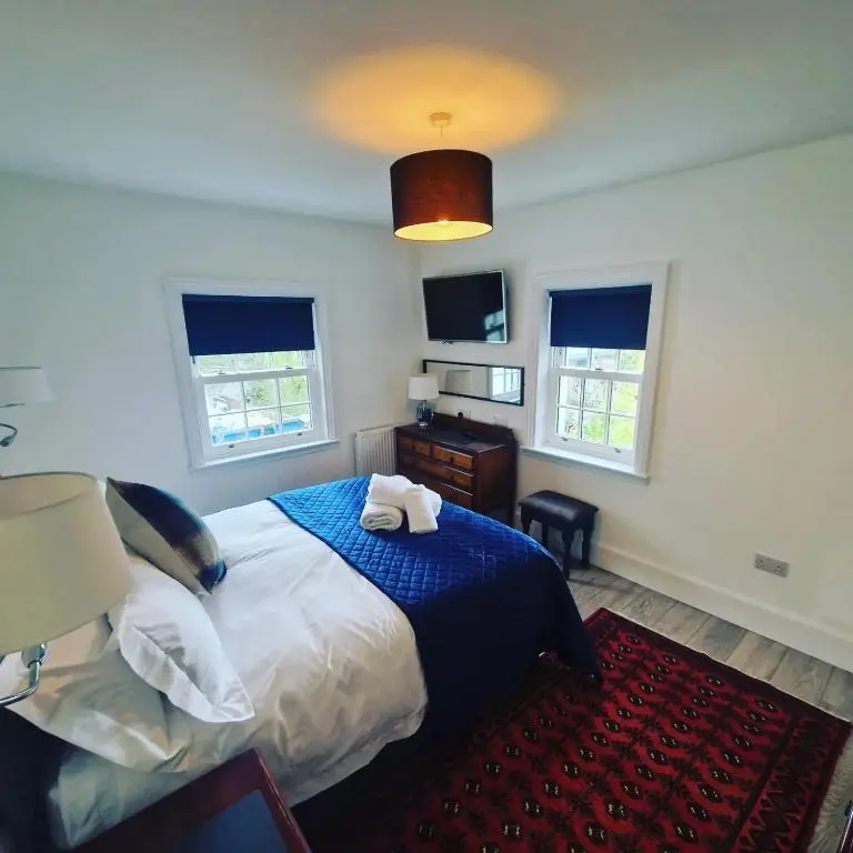a bedroom with a large bed and two windows at Conon Hotel in Dingwall