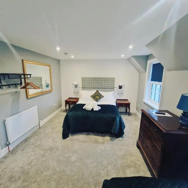 a bedroom with a bed and a dresser and a mirror at Conon Hotel in Dingwall