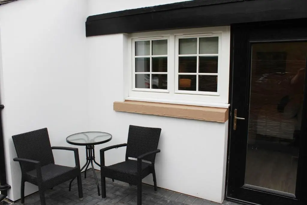 a patio with chairs and a table and a window at Conon Hotel in Dingwall