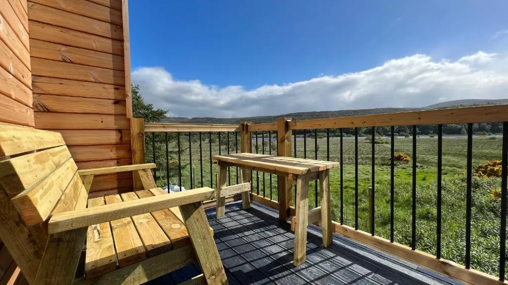 a wooden bench sitting on the deck of a cabin at Ceol Mor Highland Lodges in Lairg