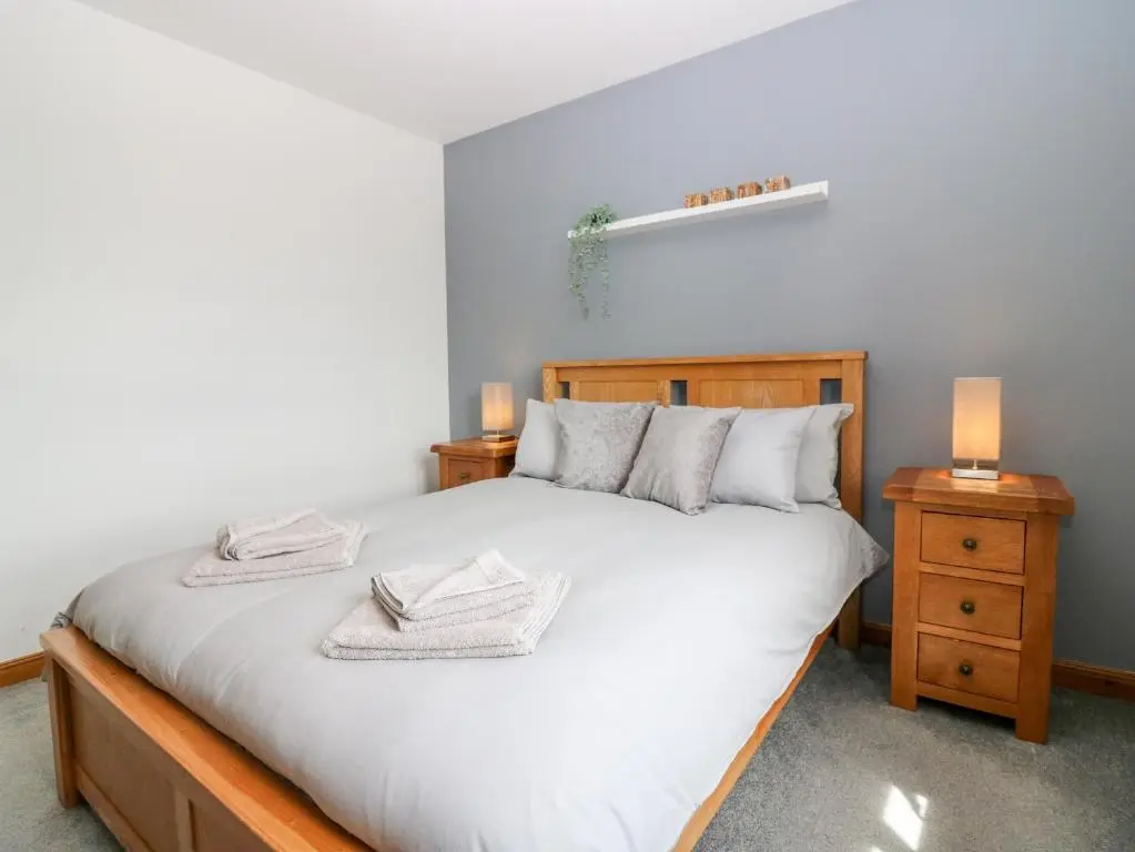 a bedroom with a large white bed with two night stands at Kilnary Cottage in Ellon