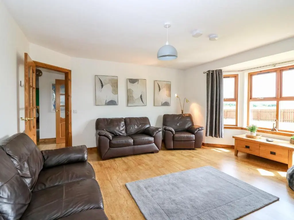 a living room with two leather couches and a table at Kilnary Cottage in Ellon