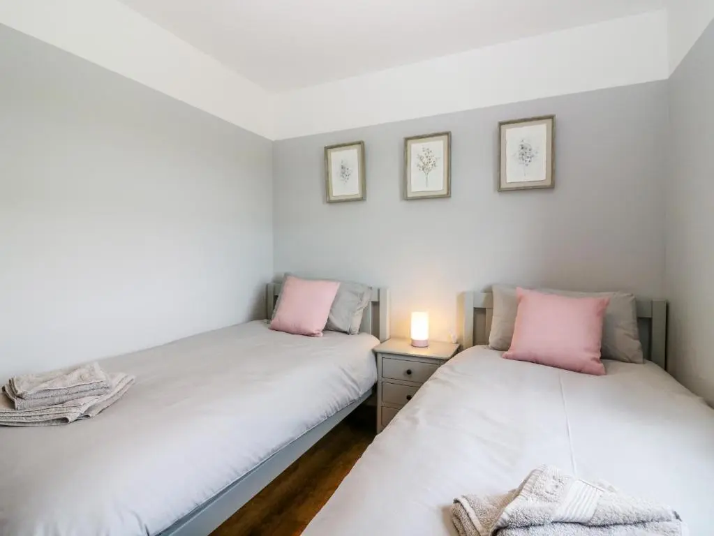 two twin beds in a small room with a lamp at Kilnary Cottage in Ellon