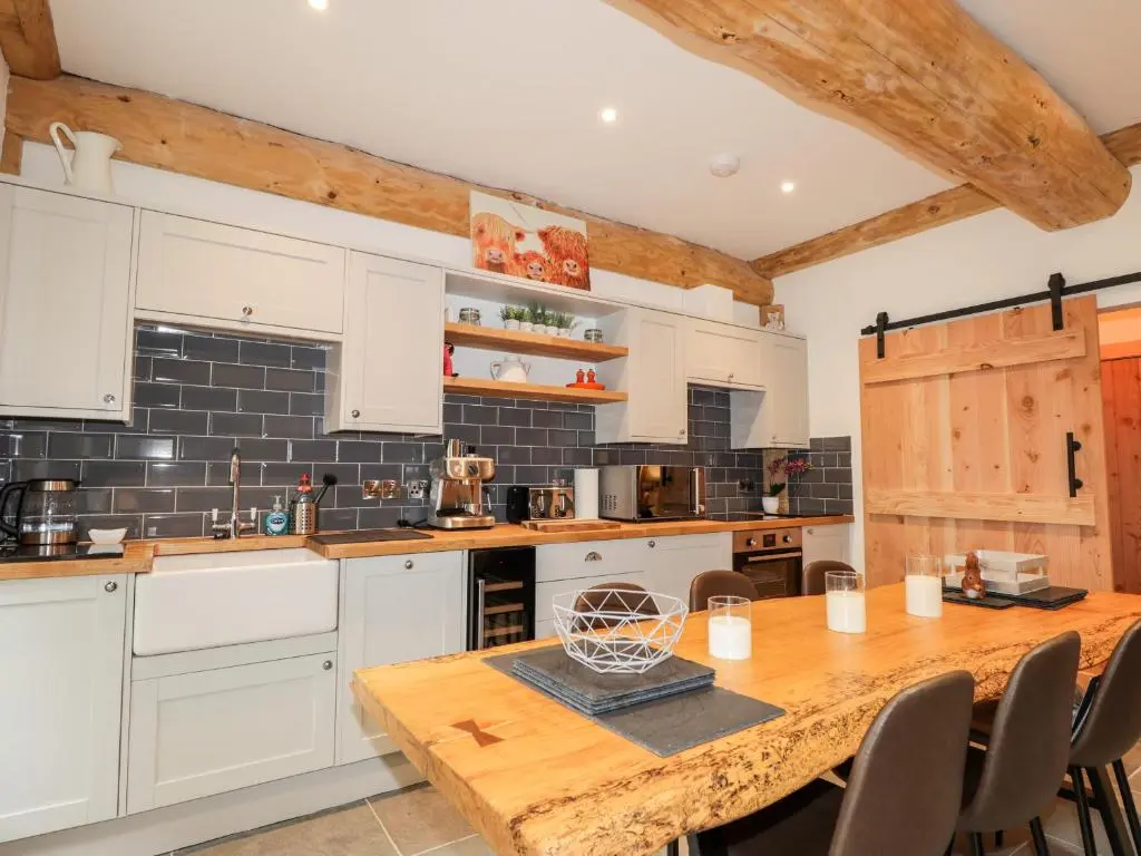 a kitchen with white cabinets and a wooden table at Pine Marten Lodge in Grantown on Spey