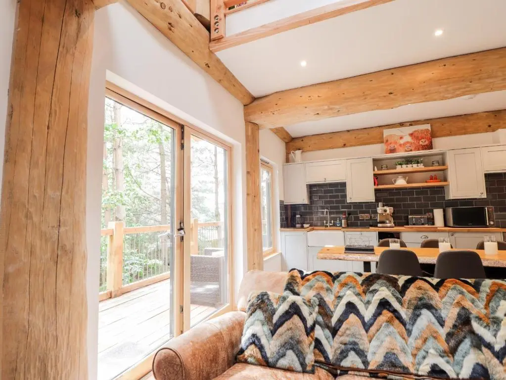 a living room with a couch and a large window at Pine Marten Lodge in Grantown on Spey