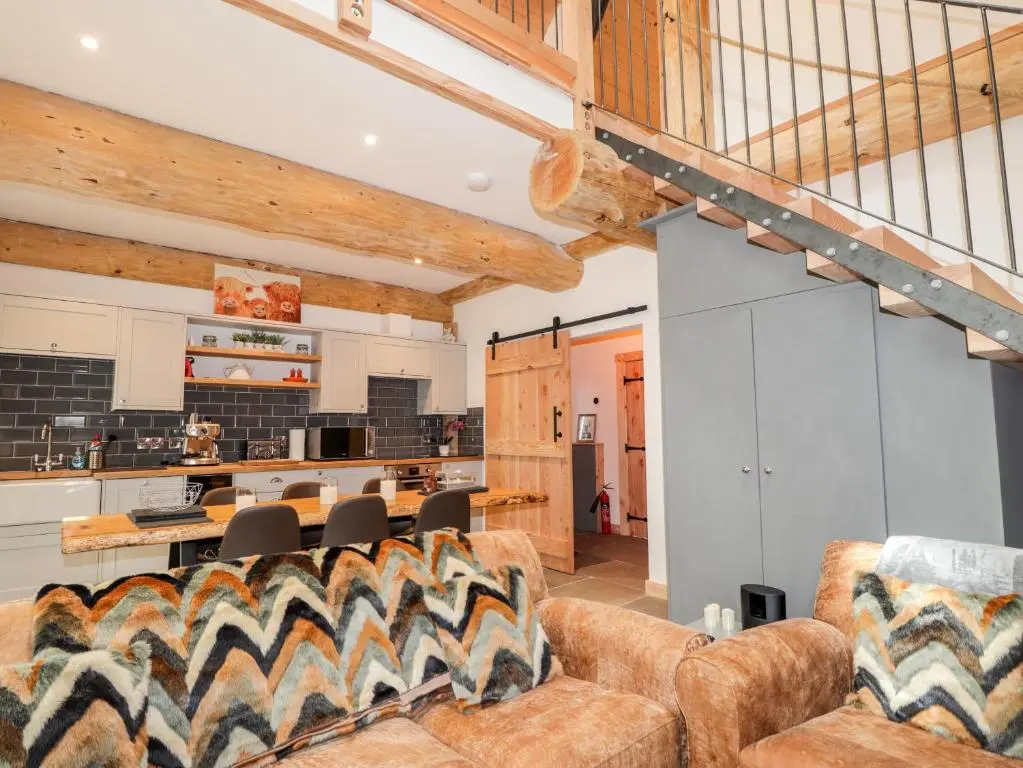 a living room with a couch and a kitchen at Pine Marten Lodge in Grantown on Spey