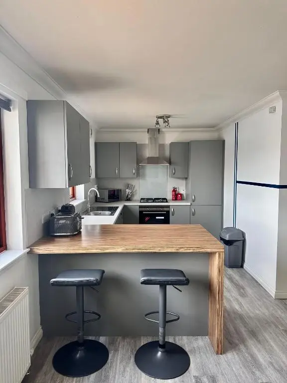 a kitchen with two bar stools at a counter at The Meadow, River view apartment in South Kessock