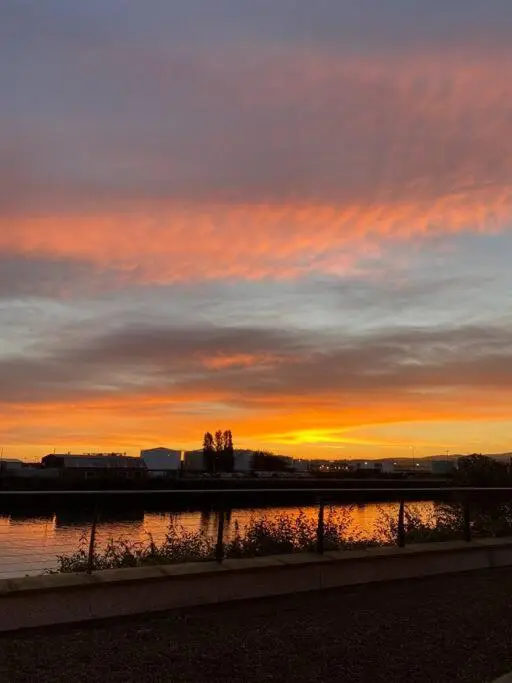 a sunset over a body of water with a fence at The Meadow, River view apartment in South Kessock