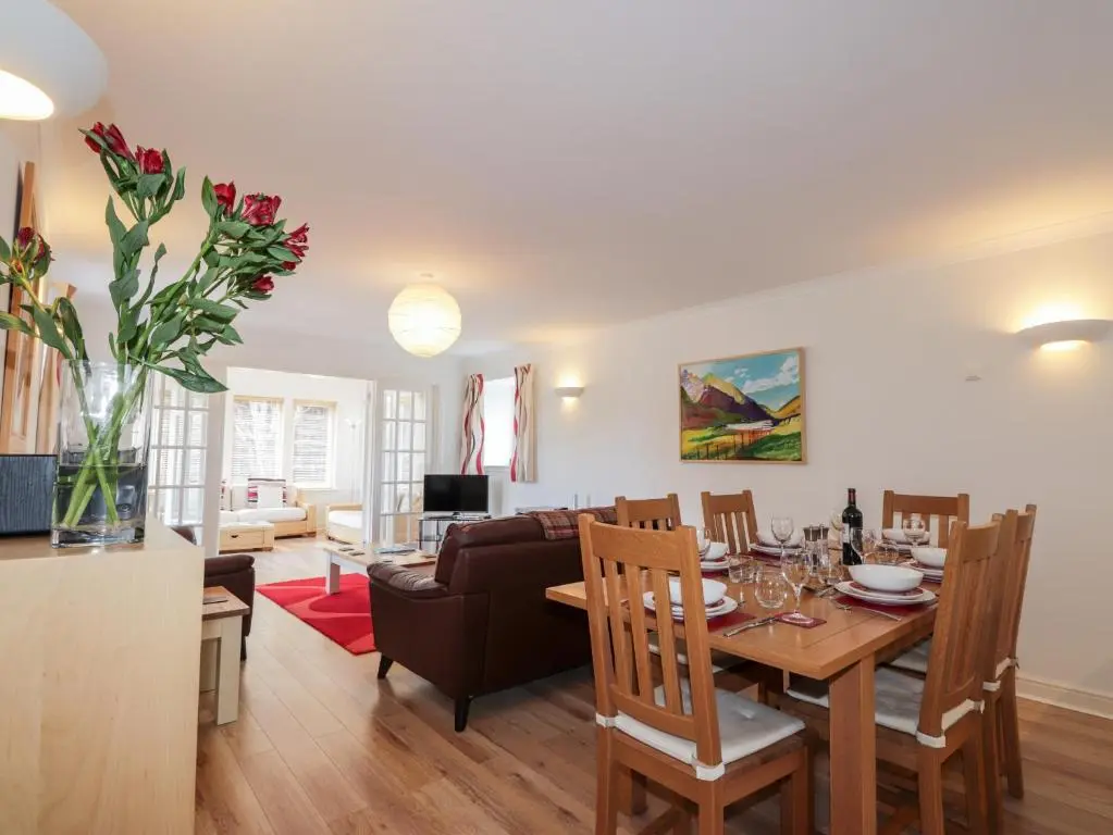 a dining room and living room with a table and chairs at Redburn Steading in Nairn