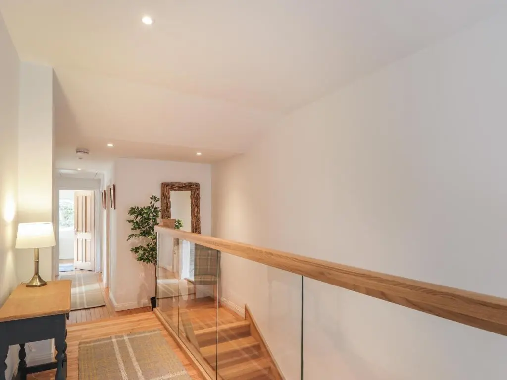 a hallway with a staircase with a table and a mirror at Old Manse in Muir of Ord