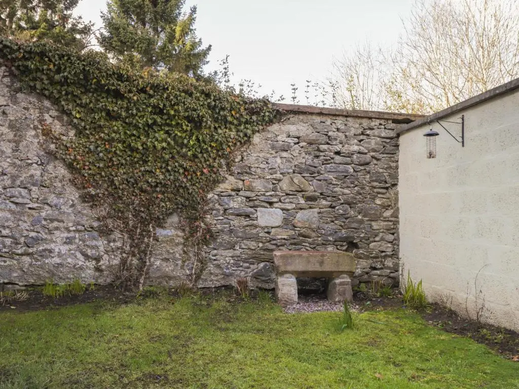 a stone bench sitting next to a stone wall at Old Manse in Muir of Ord