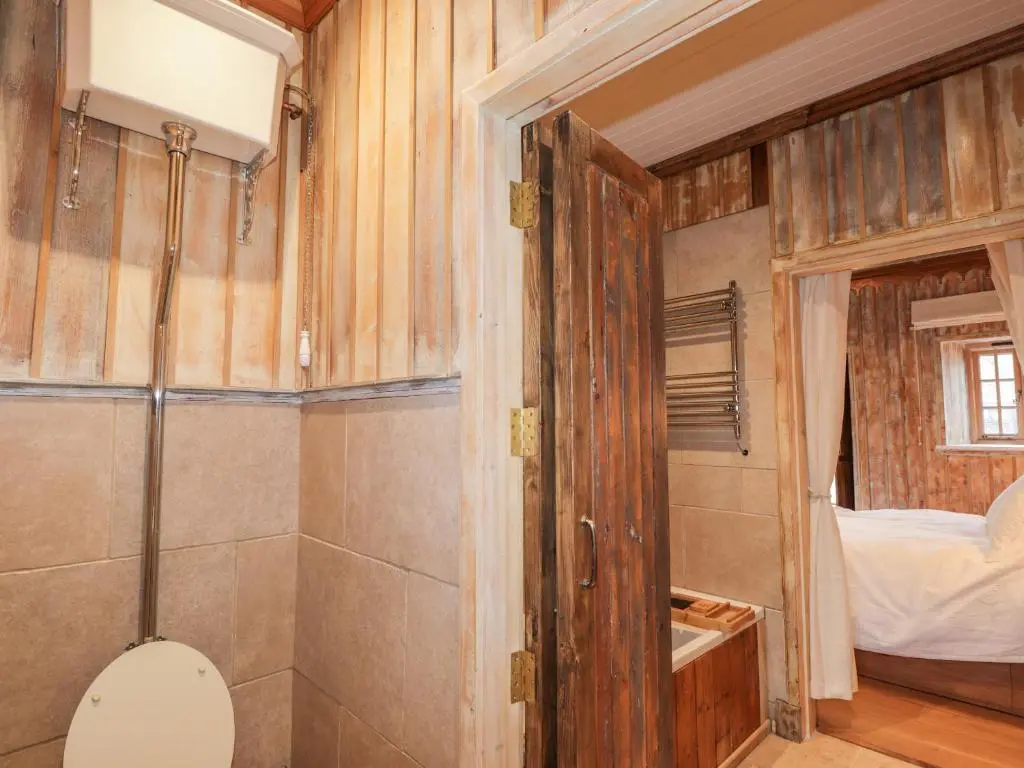 a bathroom with a toilet and a bedroom at The Hen House in Beauly