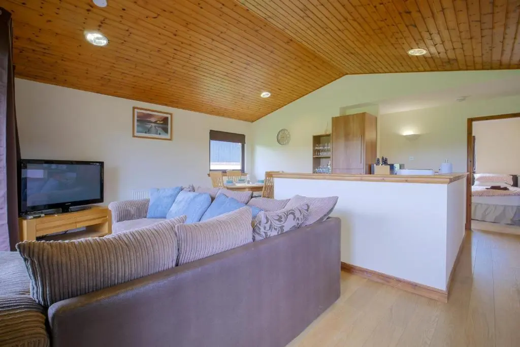a living room with a couch and a tv at Glenview Chalet Park in Inverness