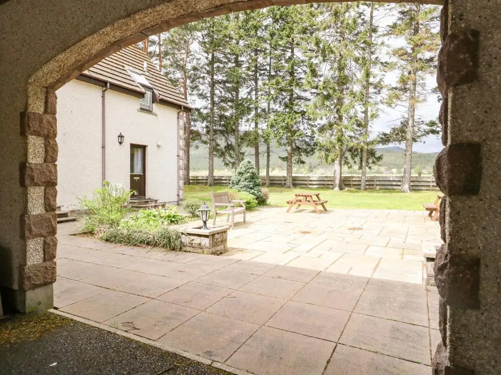 an archway leading to a patio with picnic tables and benches at The Shieling in Newtonmore