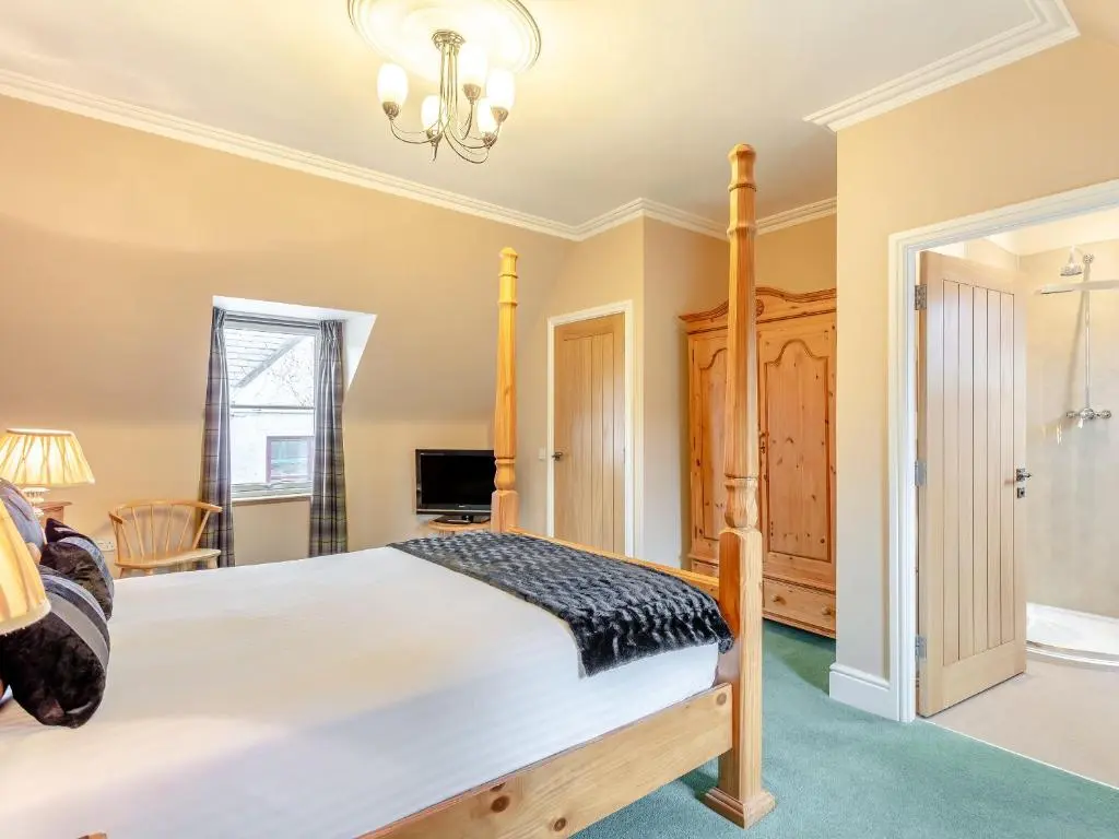 a bedroom with a bed and a chandelier at Rose Cottage - Uk39245 in Inverness