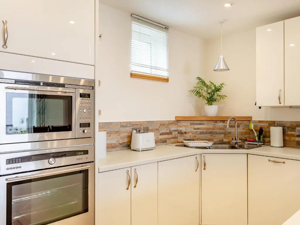 a kitchen with white cabinets and stainless steel appliances at Rose Cottage - Uk39245 in Inverness