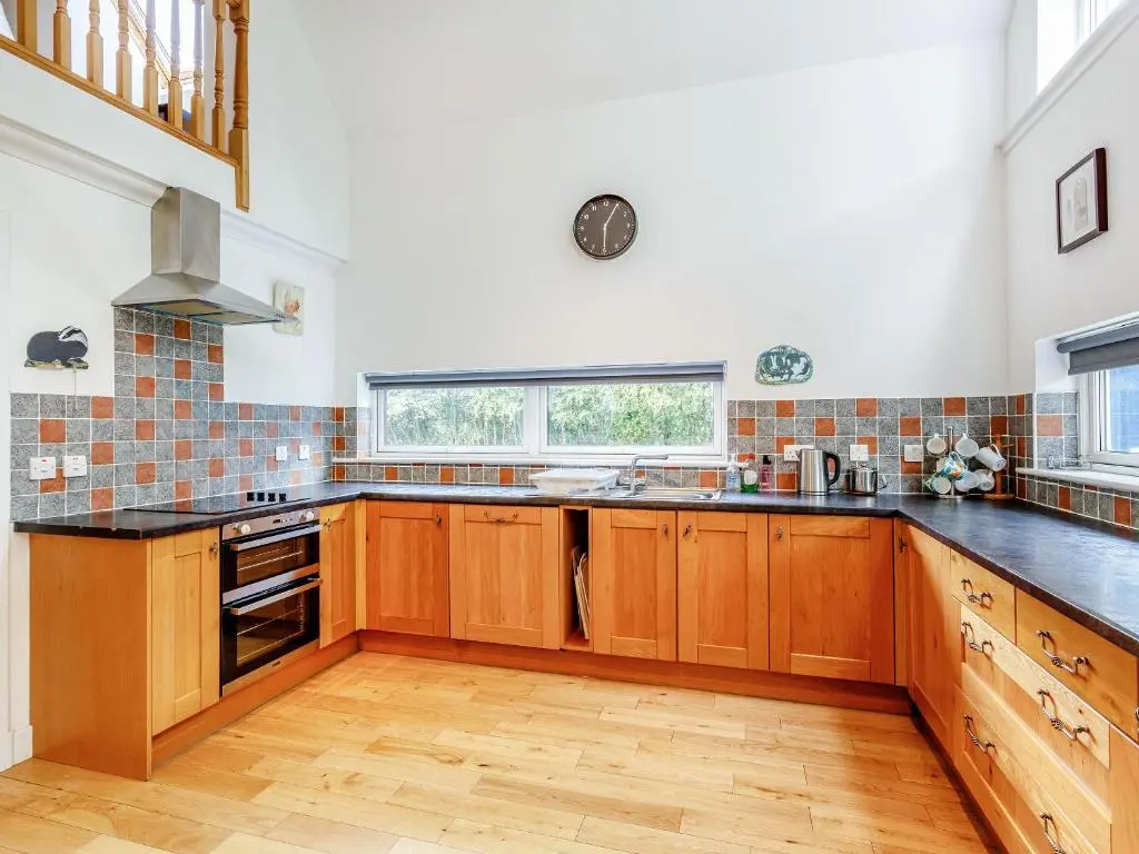 a kitchen with wooden cabinets and black counter tops at Osprey Cottage- Ukc5519 in Boat of Garten