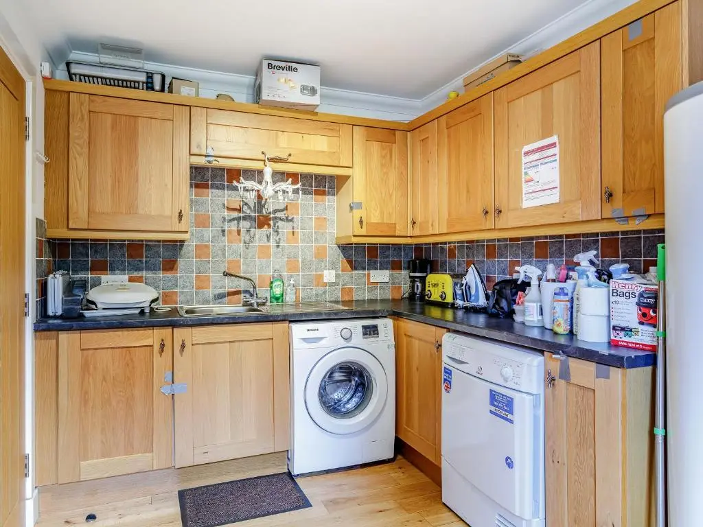 a kitchen with wooden cabinets and a washer and dryer at Osprey Cottage- Ukc5519 in Boat of Garten