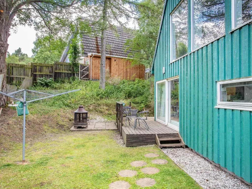a green house with a deck and a grill at Osprey Cottage- Ukc5519 in Boat of Garten