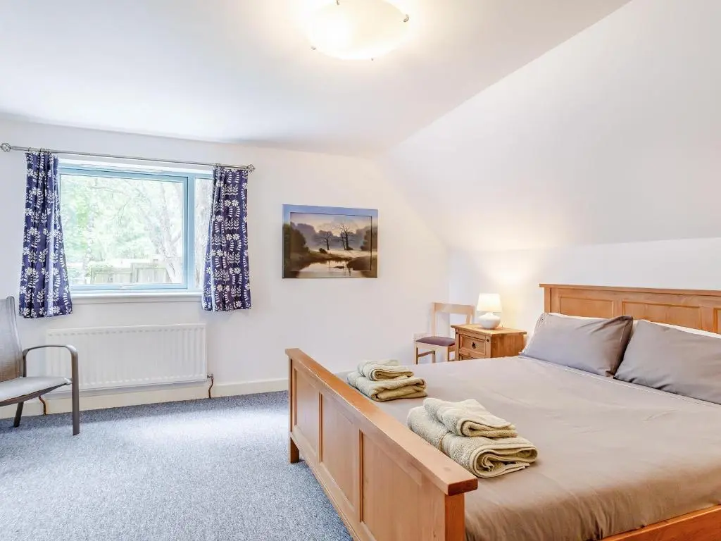 a bedroom with a bed and a window at Ptarmigan Cottage-Ukc5518 in Boat of Garten