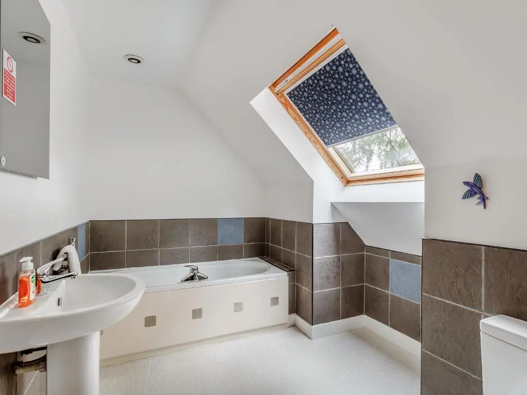 a bathroom with a bath tub and a sink at Ptarmigan Cottage-Ukc5518 in Boat of Garten
