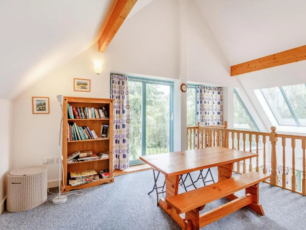 a dining room with a table and a book shelf at Ptarmigan Cottage-Ukc5518 in Boat of Garten