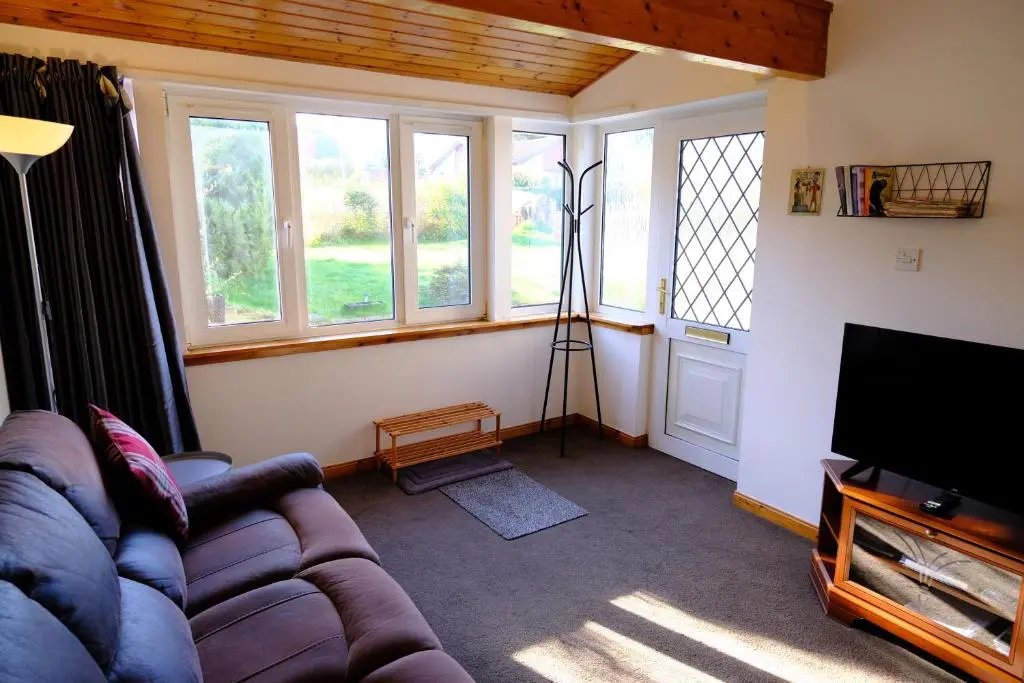 a living room with a couch and a television at Lovely 1-bedroom apartment with free parking in Inverness