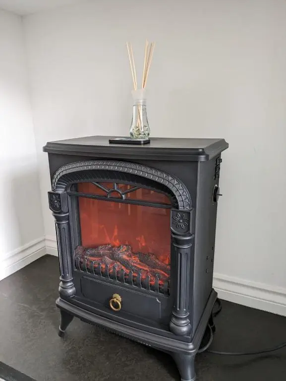 a black stove with a fire in a room at 2 Bedroom Townhouse with Seaview on the NC500 Wick in Wick