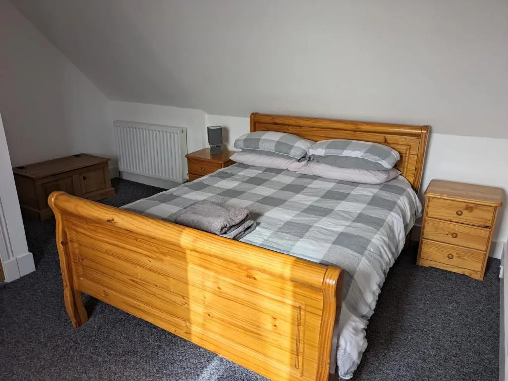 a bedroom with a wooden bed with a checkered blanket at 2 Bedroom Townhouse with Seaview on the NC500 Wick in Wick