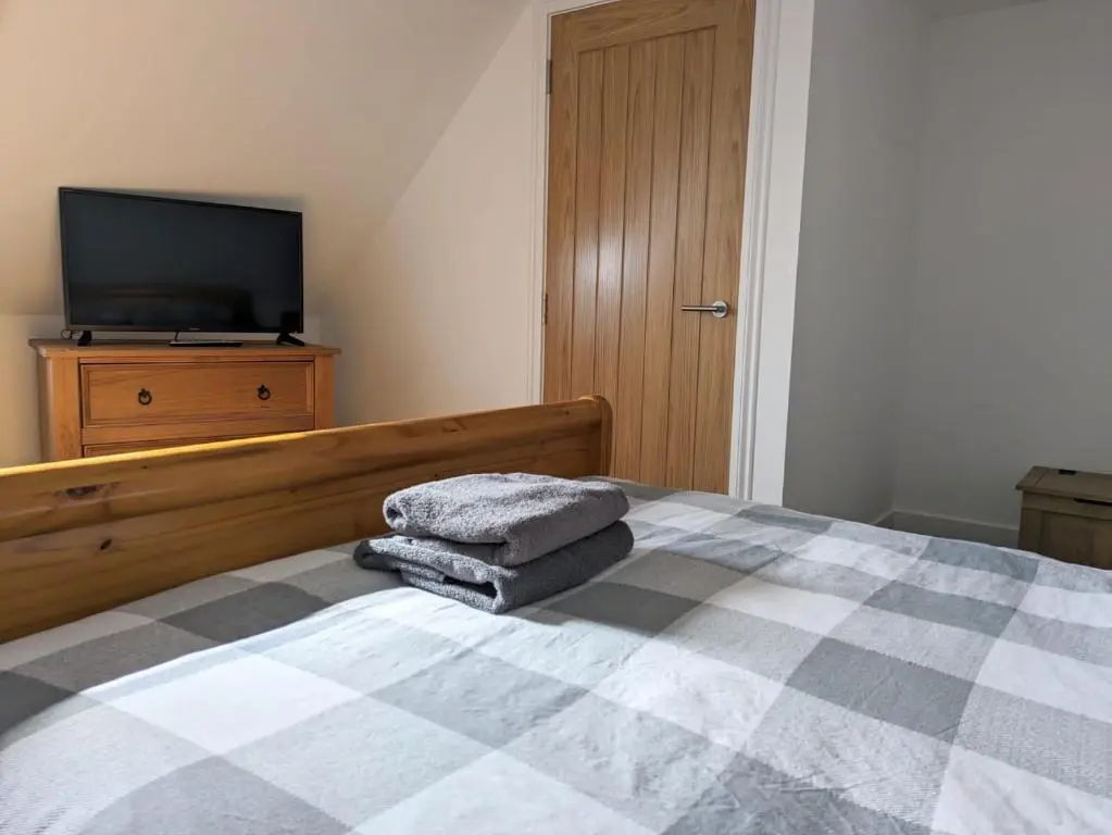 a bedroom with a bed with a television on a dresser at 2 Bedroom Townhouse with Seaview on the NC500 Wick in Wick