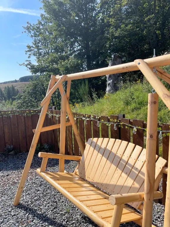 a wooden rocking chair sitting in a garden at Kaoglen-Stags Suite-Hot tub-Cairngorms- Dog Friendly in Balnald