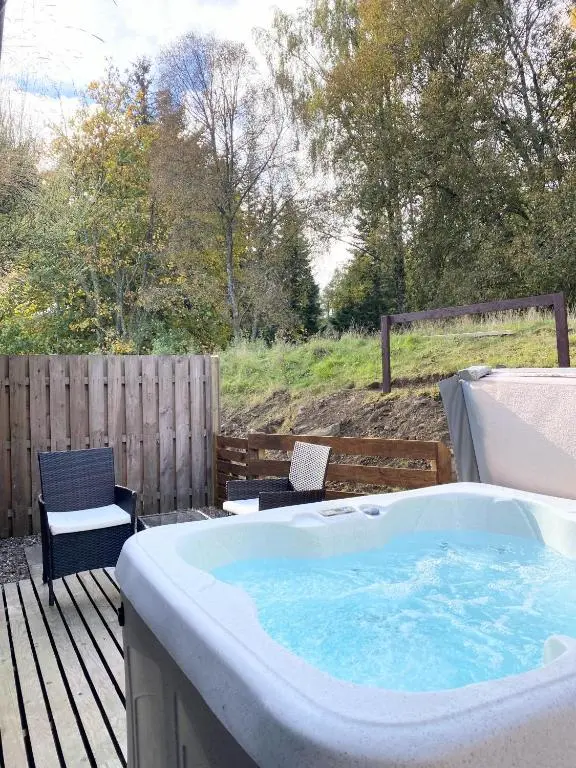 a hot tub on a deck with two chairs at Kaoglen-Blossom-Hot tub-Cairngorms-Pet Friendly in Balnald