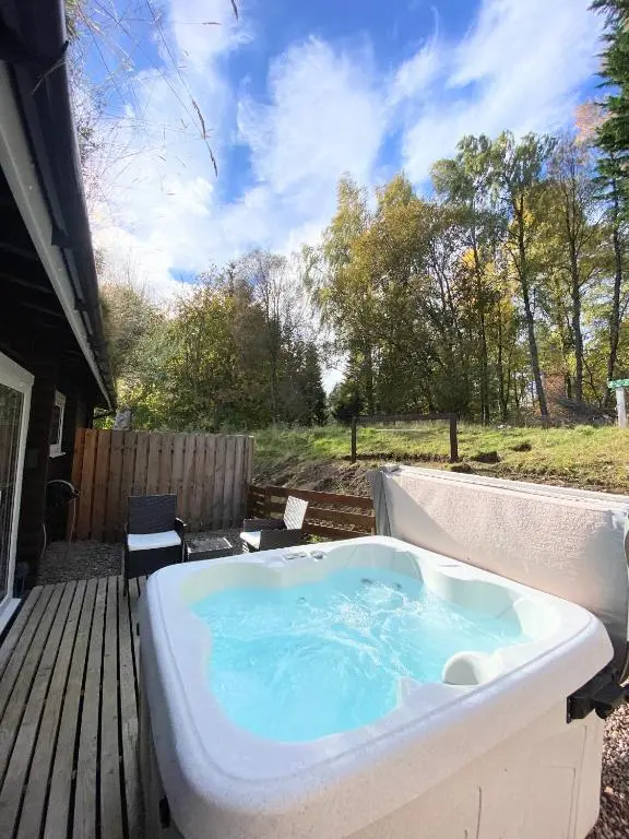 a jacuzzi tub on a deck in a yard at Kaoglen-Blossom-Hot tub-Cairngorms-Pet Friendly in Balnald