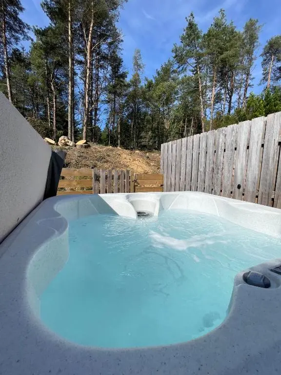 a hot tub in a backyard with a wooden fence at Kaoglen Apollo-Hot tub-Cairngorms-Pet friendly in Balnald