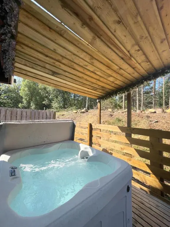 a hot tub sitting under a wooden roof at kaoglen Wild-Hot tub-Cairngorms-Pet Friendly in Balnald