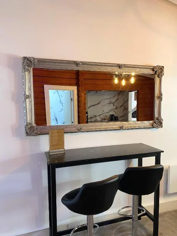 a mirror with two chairs in front of a table at kaoglen Wild-Hot tub-Cairngorms-Pet Friendly in Balnald