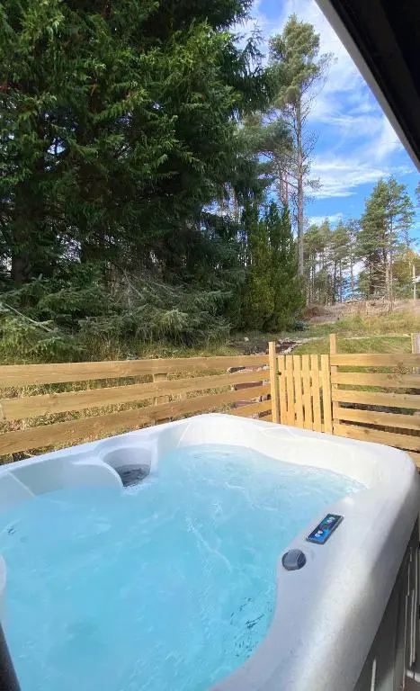 a hot tub in a backyard with a wooden fence at kaoglen Wild-Hot tub-Cairngorms-Pet Friendly in Balnald